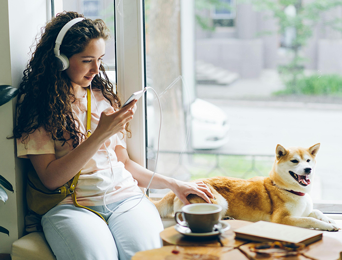 A young woman watching a video on her phone with a dog by her side